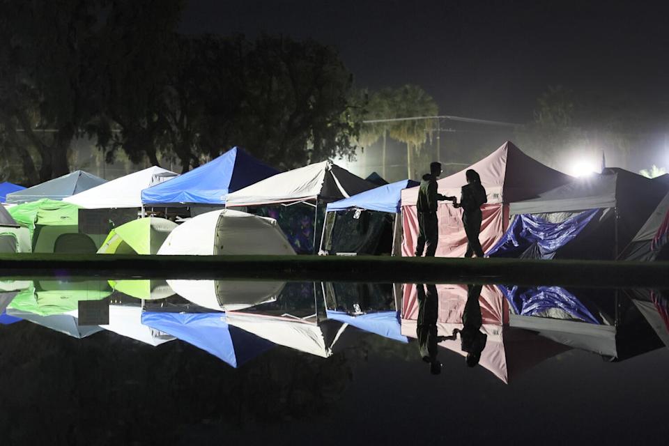Campers and canopies are reflected in the lake as they head back to their campground at Coachella.