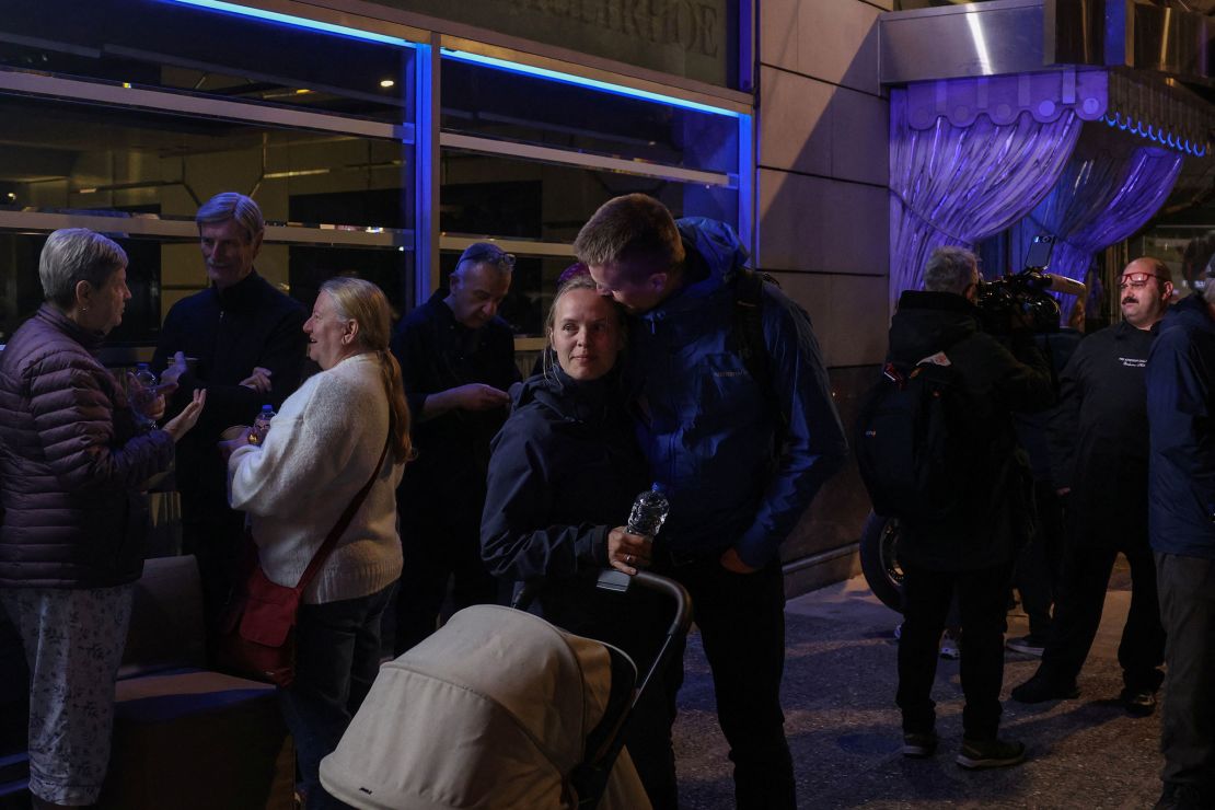 A man embraces his partner as customers of a nearby hotel stand on the street following a bomb blast outside the Hellenic Train offices, in Athens, Greece, on April 11, 2025.