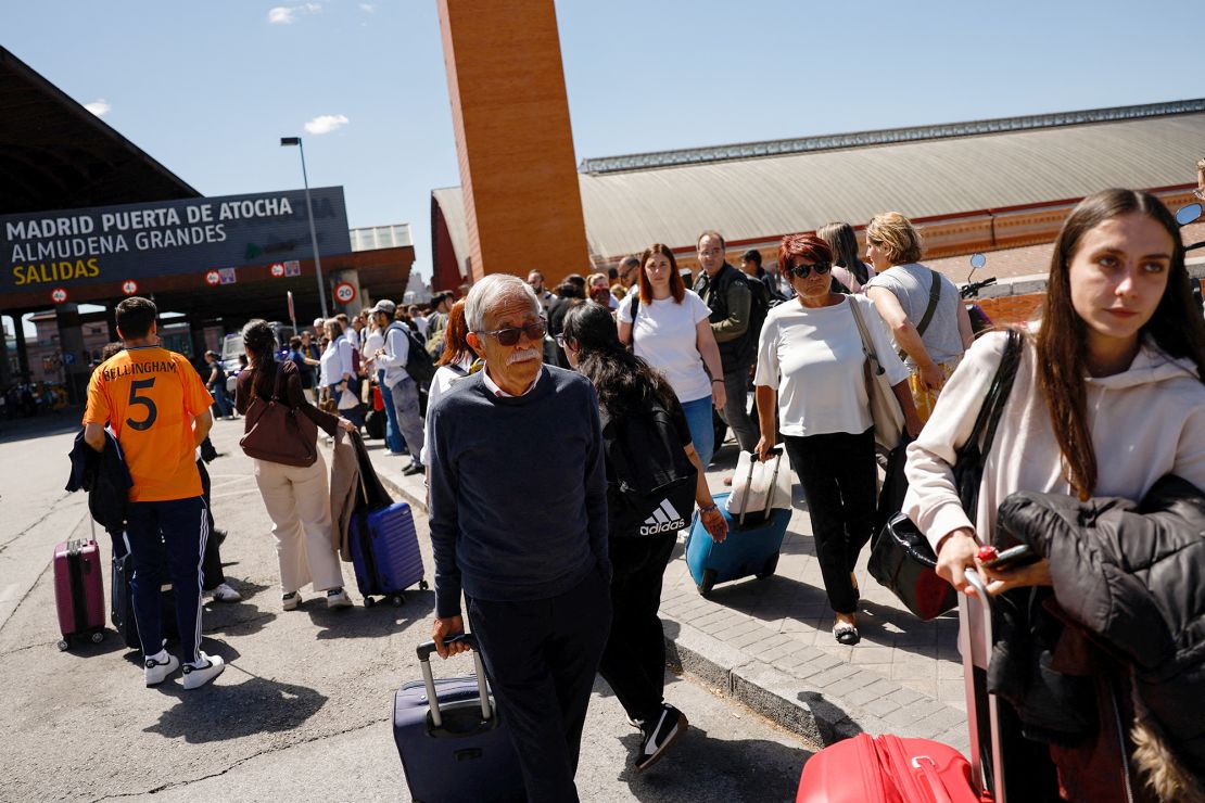 Travellers walk outside Atocha train station with their luggage after it was closed due the outage.