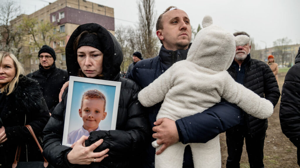 Russia continues to rain down death on Ukrainian cities Parents hold portrait of their son killed in Russian missile strike near a makeshift memorial on a playground.