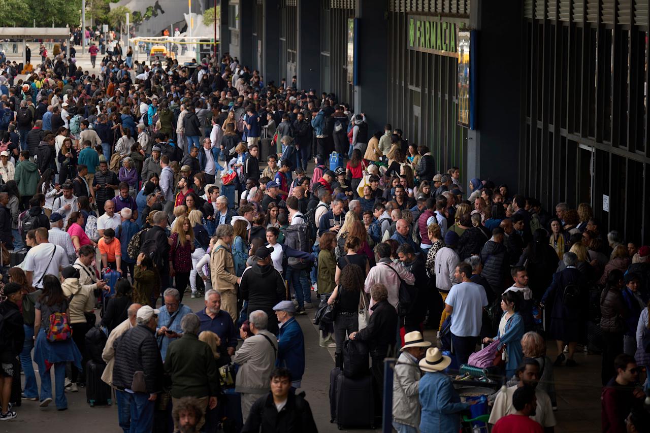 People wait outside a closed train station, during a major power outage in Barcelona, Spain, Monday, April 28, 2025. (AP Photo/Emilio Morenatti)