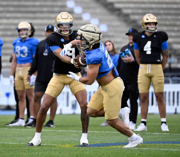 Quarterback Dermaricus Davis #9 of the UCLA Bruins hands off...