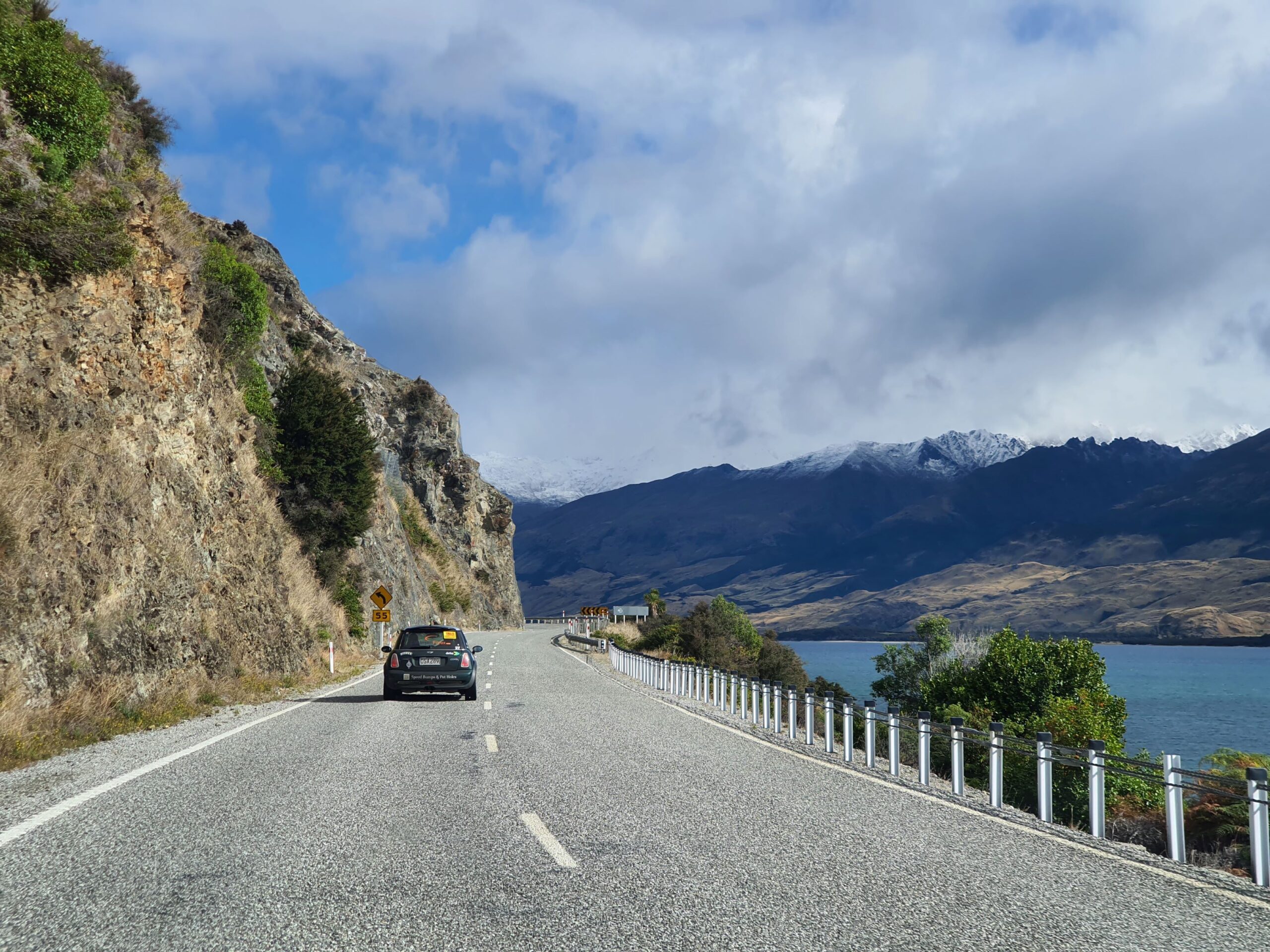 A green Mini Cooper JCW follows the road alongside Lake X with The Remarkables visible in the background on the 2025 Pork Pie Charity Run.