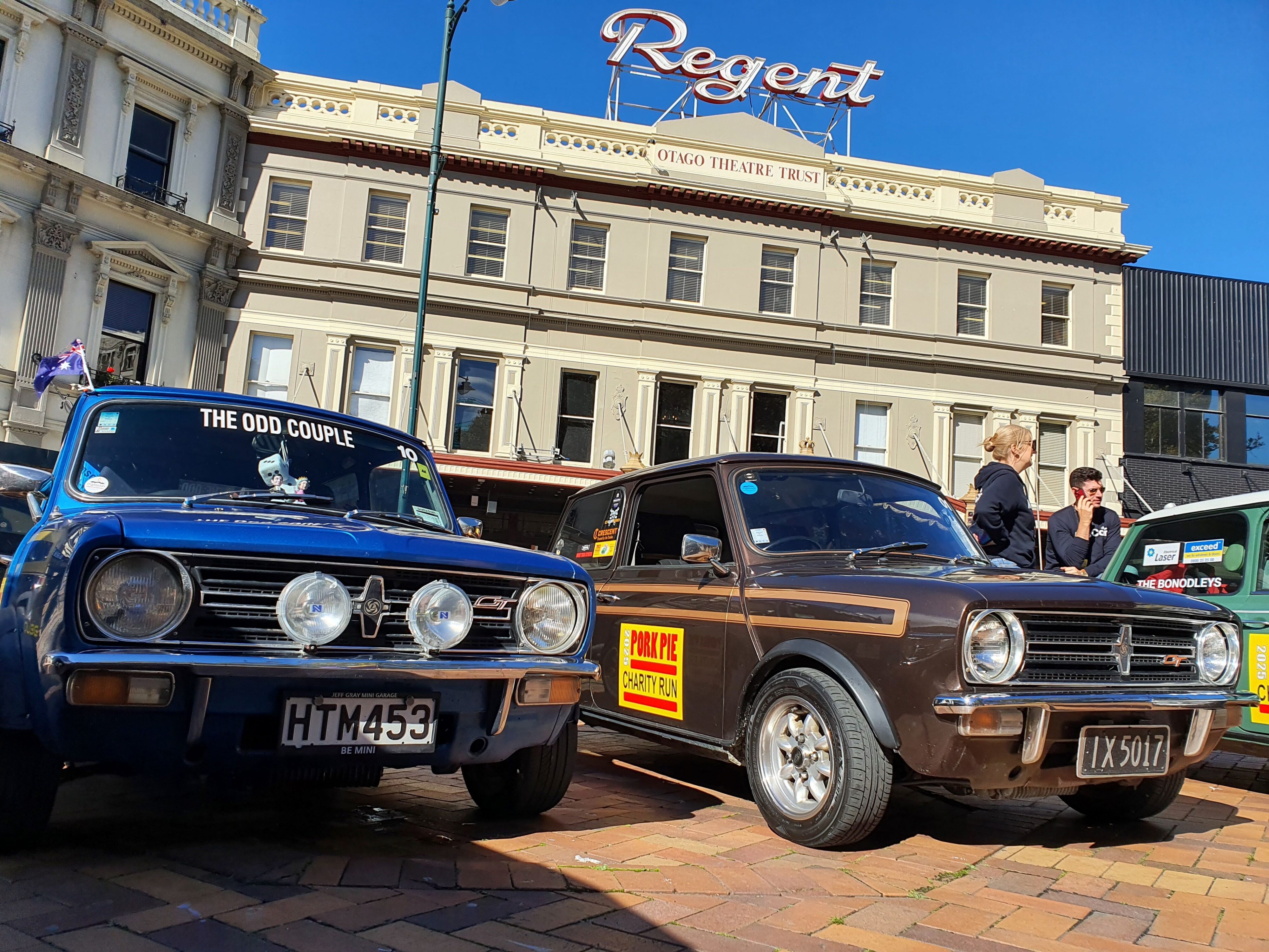 Two classic Minis parked in Dunedin's Octagon in front the The Regent Theatre on the 2025 Pork Pie Charity Run.