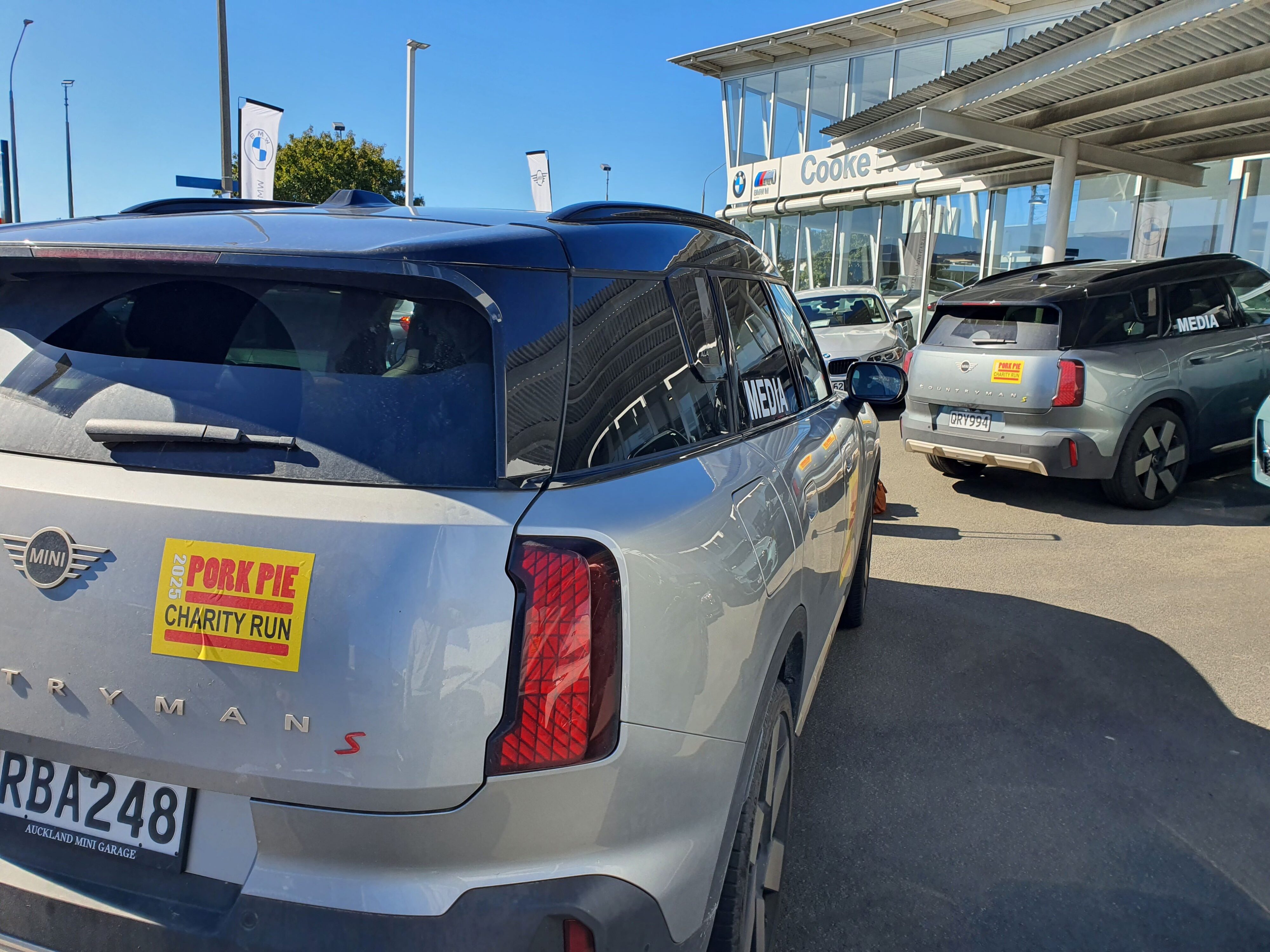 A 2025 Mini Countryman S and 2025 Mini Countryman SE with 2025 Pork Pie Charity Run stickers parked at Cooke Howlison BMW Mini in Dunedin.