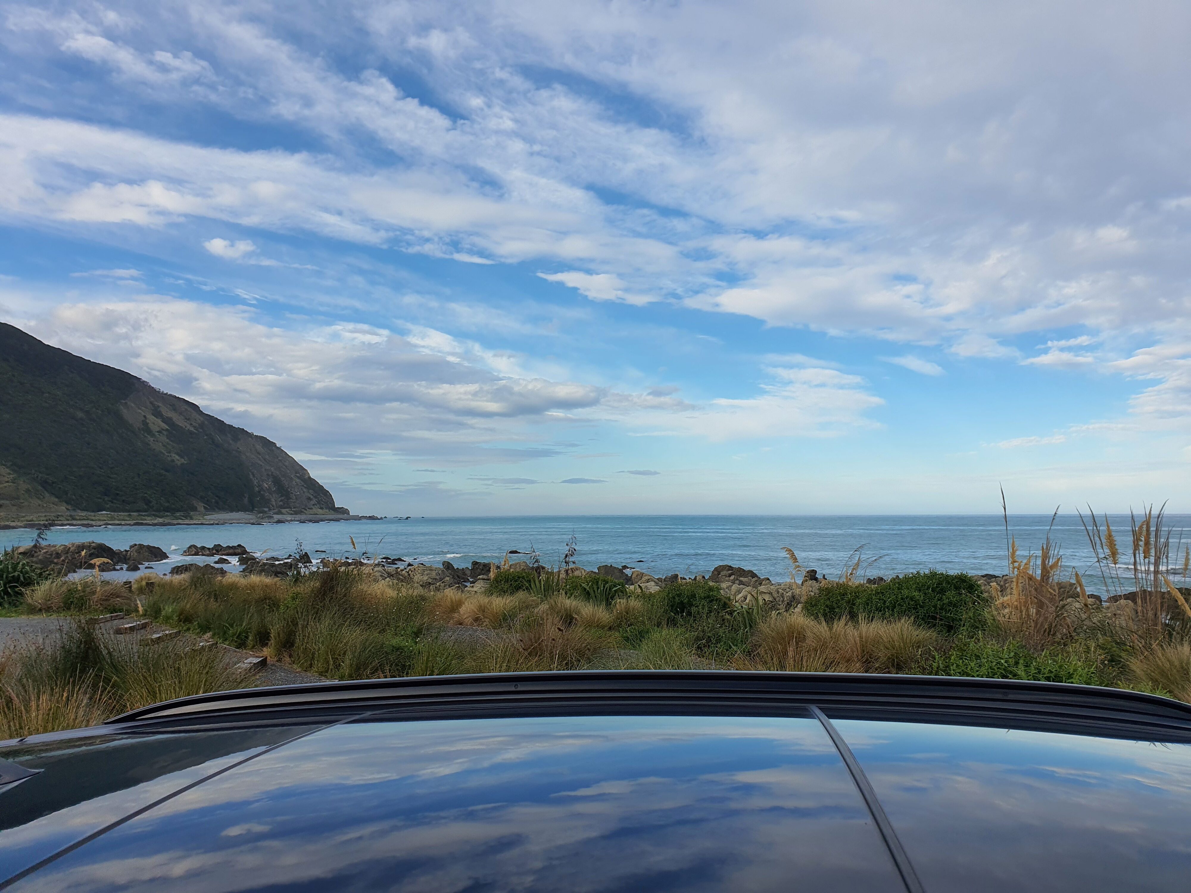 A view of the ocean outside Kaikoura with the black roof of a 2025 Mini Countryman SE visible in the foreground.