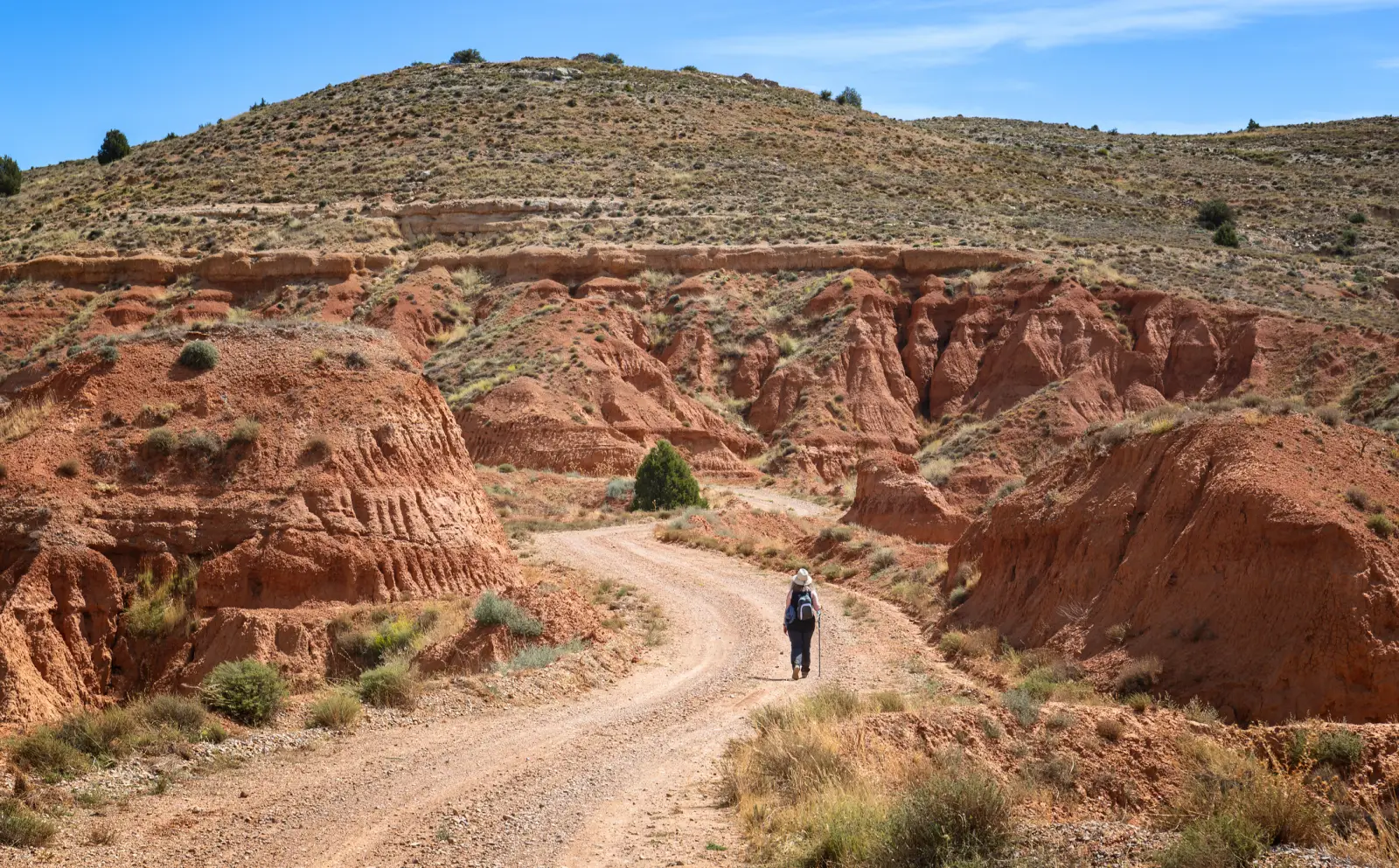 Johnny Depp Brings Dior And Spotlight To Spain’s Screen Tourism Gem 4 Hiker walking along a winding dirt trail through the red canyons of Rambla de Barrachina in Teruel, Spain