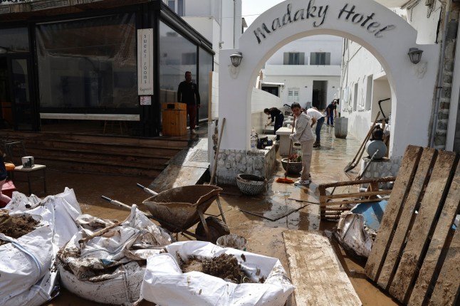 People try to clear the mud from a hotel after a powerful storm which has triggered widespread flooding at the port of Naousa, on the Aegean Sea island of Paros, Greece, Tuesday, April 1, 2025. (John Liakos/InTime News via AP)