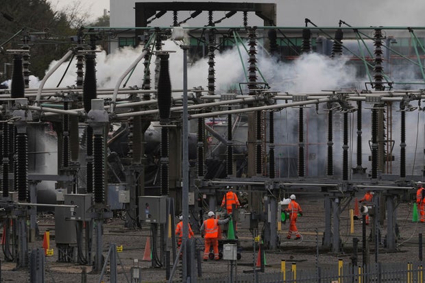 Workers are seen as smoke rises from the North Hyde electrical substation, which caught fire, leading to the closure of Heathrow Airport, in London, March 21, 2025. 