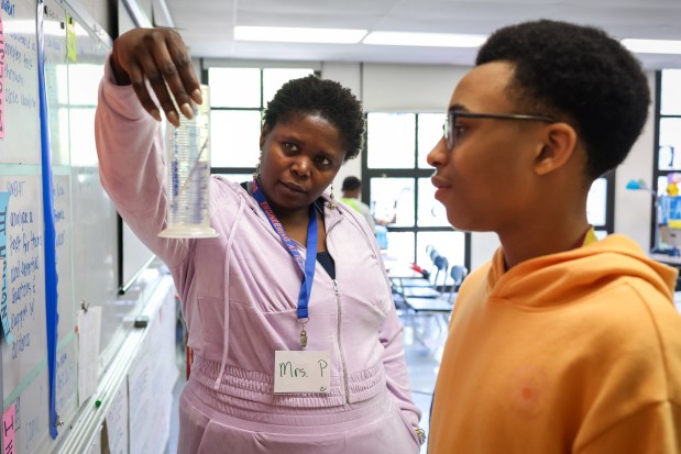 Iyabo Pommells, a former math and physics teacher, helps Kendall Burnett, 13, evaluate a buoyancy and density test during a lesson with the Chicago Pre-College Science and Engineering Program at Kenwood Academy High School. (Audrey Richardson/Chicago Tribune)