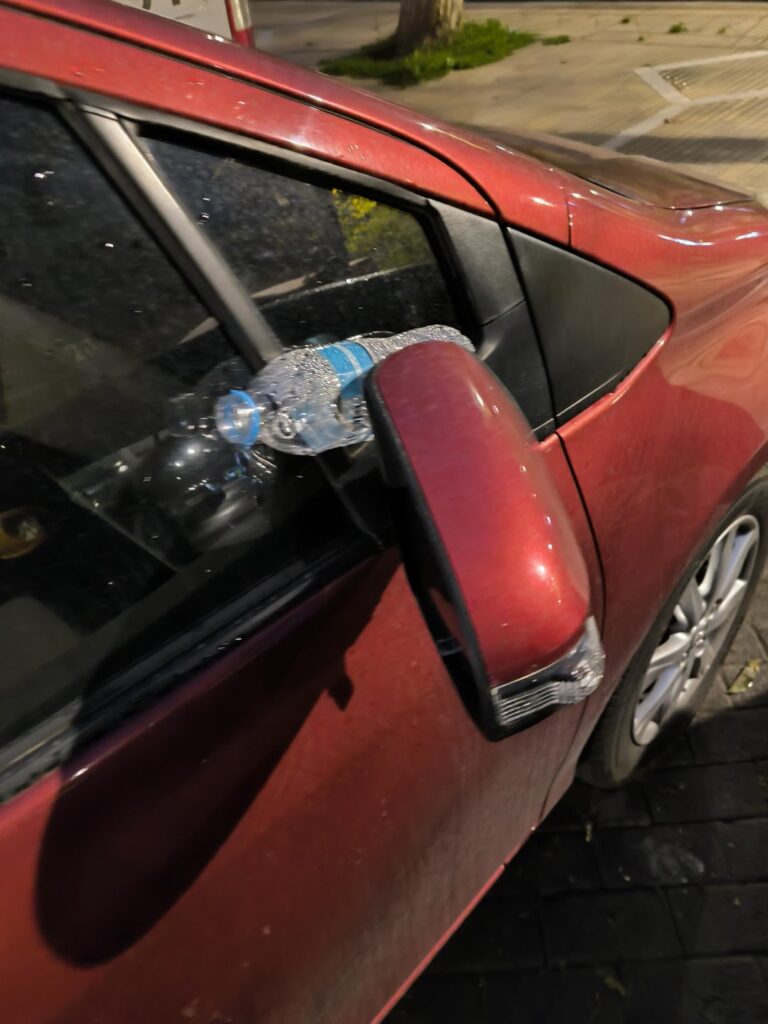 Wedged bottle of water in the car mirror. Is it a message of raised wipers?