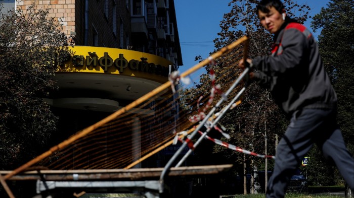 A worker pushes a cart near a branch of Raiffeisen Bank in Moscow, Russia