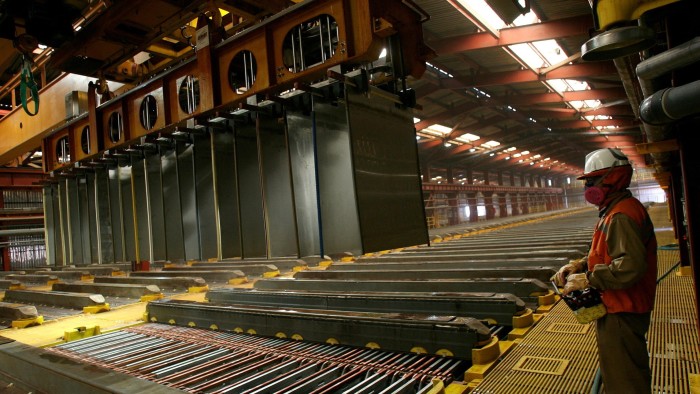 BHP says China boosting domestic consumption is key to global economy A worker at BHP's Escondida copper mine in Antofagasta, Chile, stands inside a copper cathodes plant with large metal sheets suspended from machinery and the worker wearing protective gear, including a helmet and mask