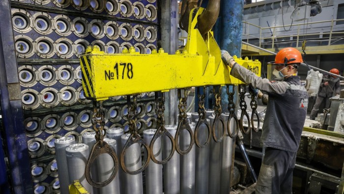 A worker prepares to secure newly cast aluminium cylinders to a hoist in the foundry at the Sayanogorsk aluminium smelter, operated by Rusal, in Sayanogorsk, Russia