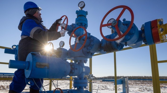 A worker turns a valve wheel at a gas well