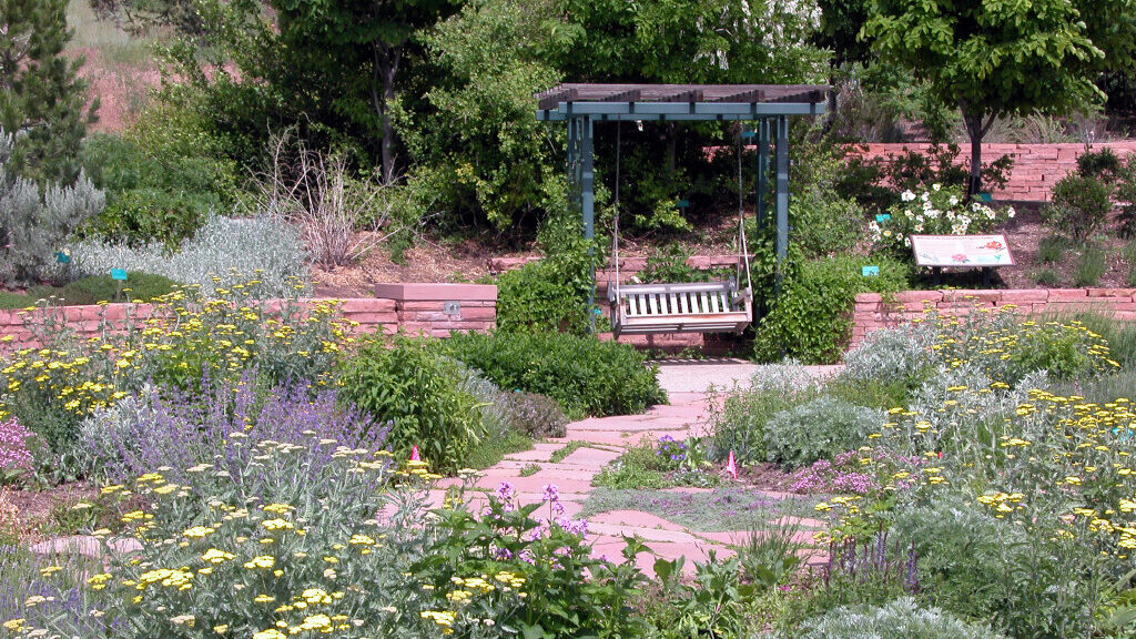 A bench sits surrounded by colorful, thriving plants in Salt Lake City's Red Butte Garden hike for ...