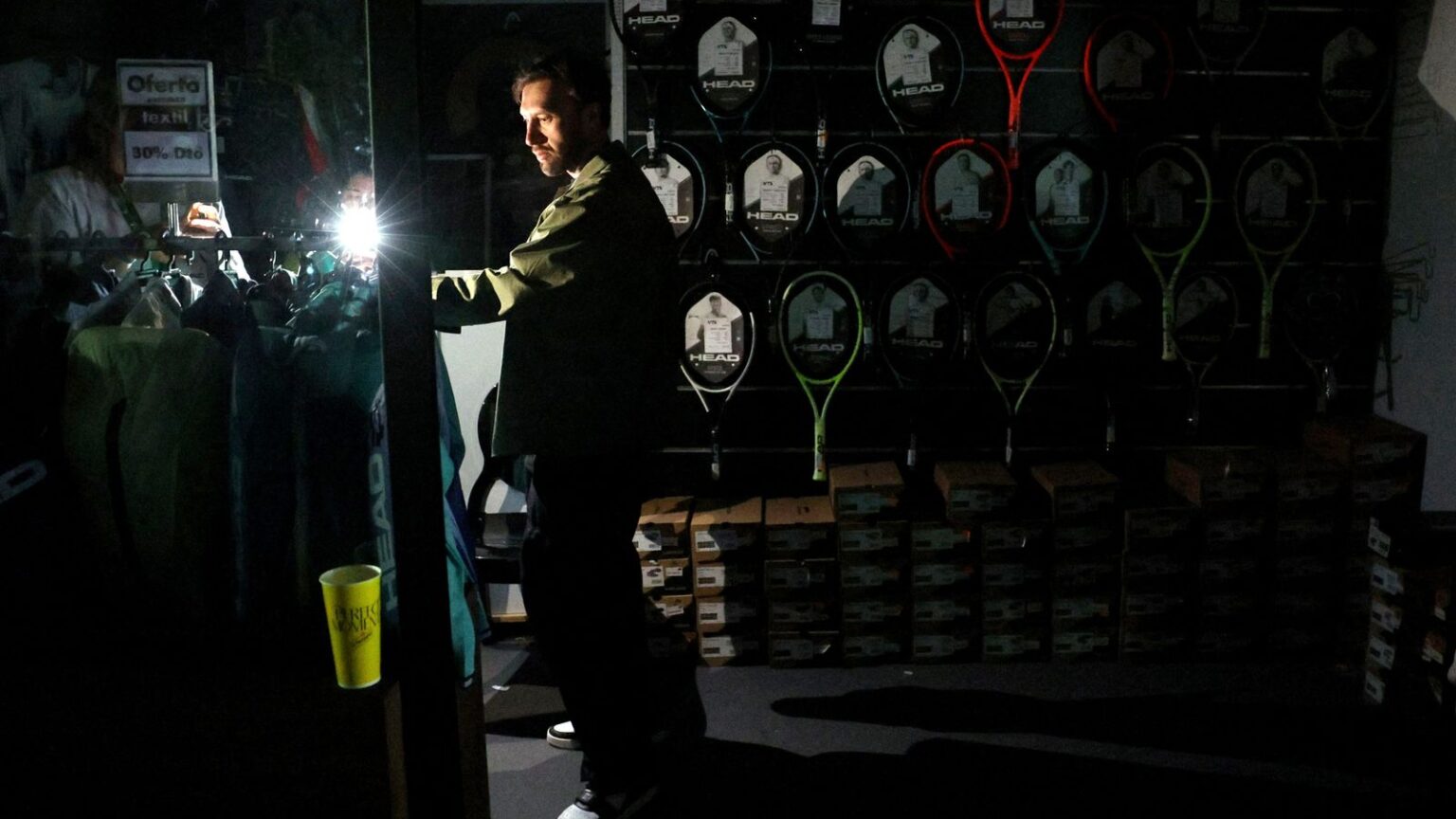 How electricity grids fail – and why restoring Spain and Portugal’s power will be a nightmare | Science, Climate & Tech News Tennis - Madrid Open - Park Manzanares, Madrid, Spain - April 28, 2025 A man uses his cell phone's flashlight in a dark sports shop after the matches get suspended due to a power outage REUTERS/Violeta Santos Moura