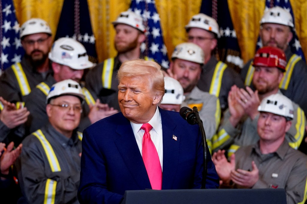 U.S. President Donald Trump signing energy-related executive orders at a podium, surrounded by coal industry workers in hard hats, at the White House, April 8, 2025.