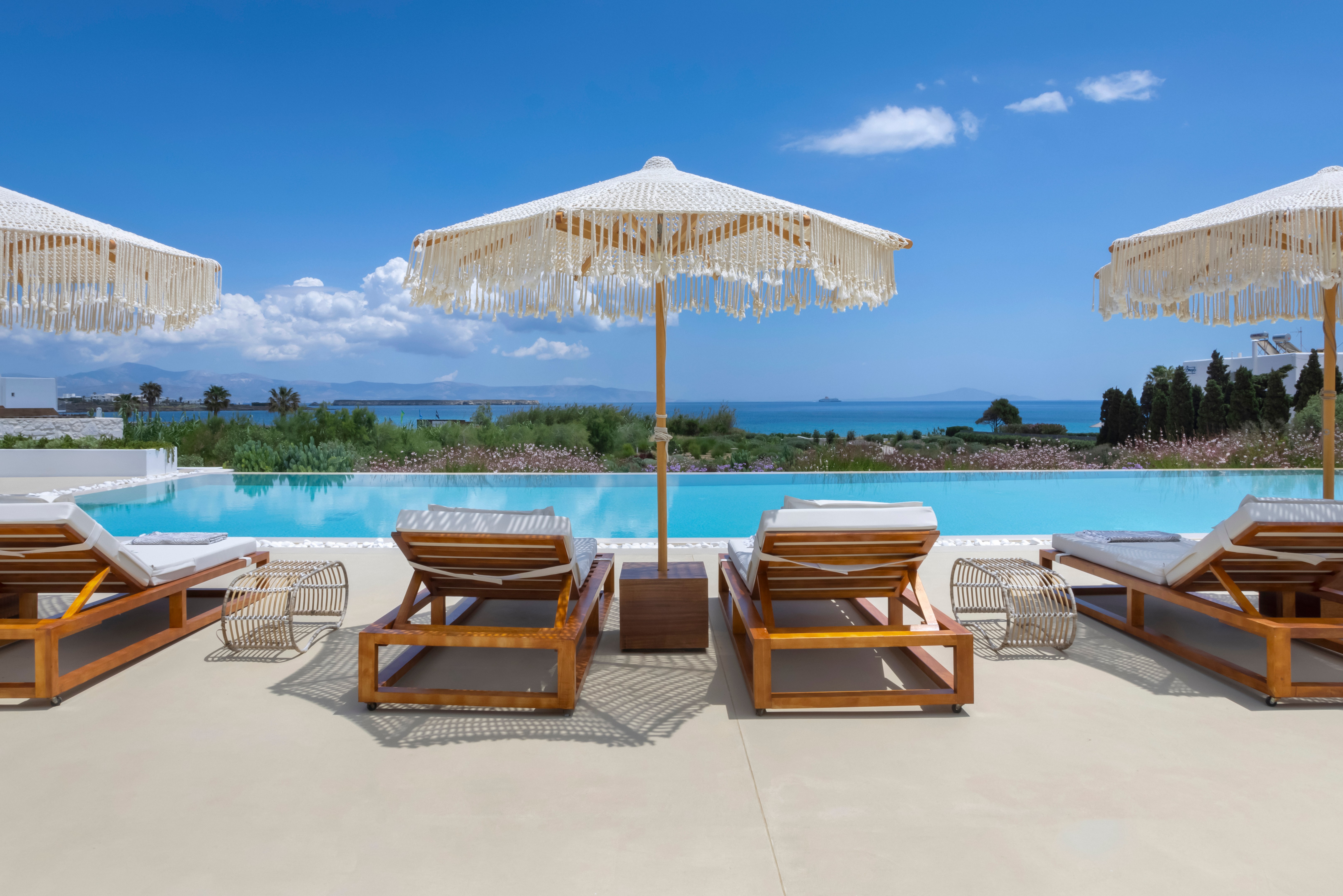 Luxury villa poolside with lounge chairs and umbrellas.