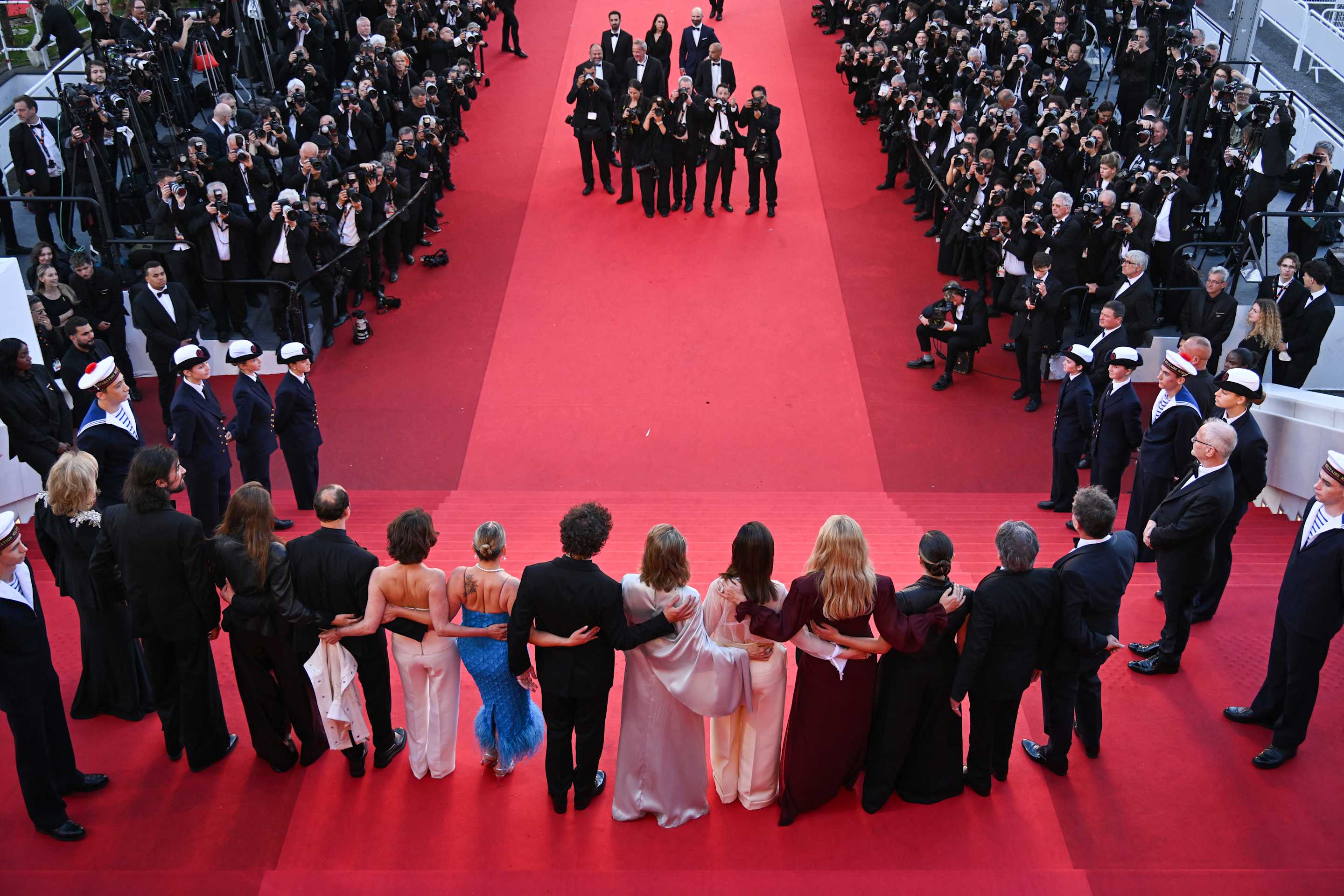 Seen from above, dozens of people on a red carpet.