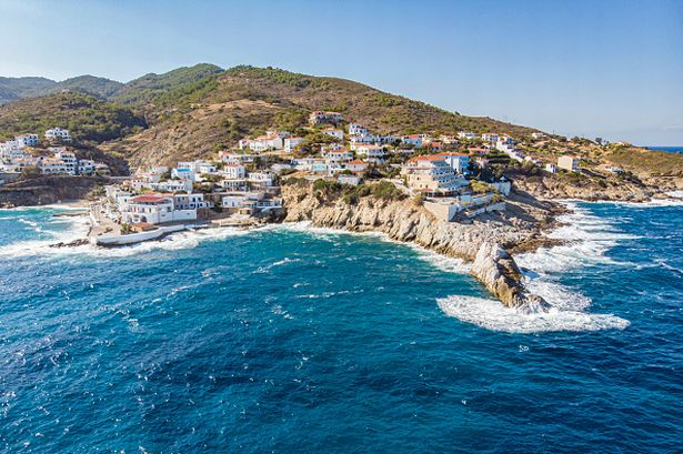 Panoramic aerial view of the traditional picturesque Armenistis village as seen from a drone, one of the most popular holiday destination on the Greek island of Ikaria located in the Aegean Sea. The Mediterranean Ikaria island is famous for the longevity and the alternative lifestyle closer to nature. Armenistis is a little fishing village on a hill, center of the local economy of Icaria, with a sandy beach  with transparent crystal clear water, hotel, rooms to let, super market, local shops, restaurant, taverns, bar and other facilities. A popular travel destination for summer holidays. Ikaria Island, Greece on November 2022 (Photo by Nicolas Economou/NurPhoto via Getty Images)