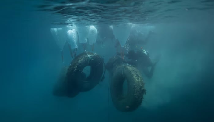Volunteer divers lift tyres from the bottom of the seabed, off the island of Alonissos, Greece, May 25. — Reuters