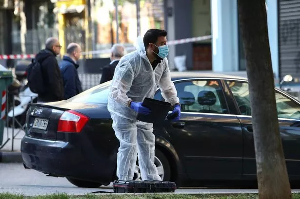 A Greek police forensic expert searches for evidence at the area where a 38-year-old woman was killed early Saturday when a bomb she was carrying exploded in her hands outside a bank branch, local police said, in Thessaloniki, northern Greece, May 3, 2025.