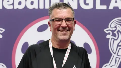 Kieran Cleeves/Pickleball England Richard Love, a man who is looking at the camera and smiling. He is wearing a black sports top and has a medal round his neck. 