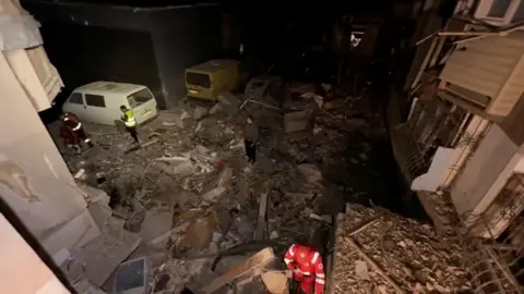 Reuters Emergency services work at a site damaged during a Russian drone attack in Odesa, Ukraine, in this screengrab from a video released by mayor Hennadii Trukhanov on Telegram.
