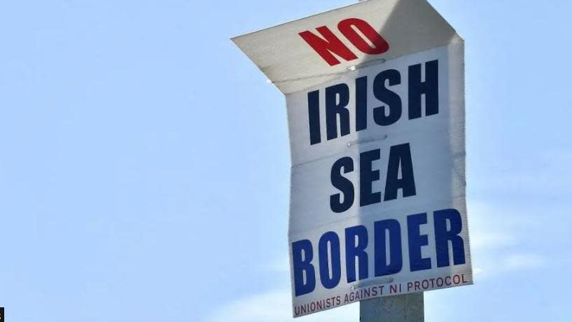 A poster on a lamp post that says 'No Irish Sea Border' and in smaller writing at the bottom it says 'Unionists against NI Protocol'. In the background is a blue sky