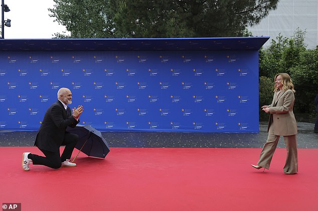 Putting his umbrella to one side as she strode towards him on the red carpet, he then put his hands together as if in prayer before they embraced