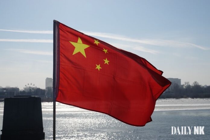 The flag of China with a view of a river behind it.