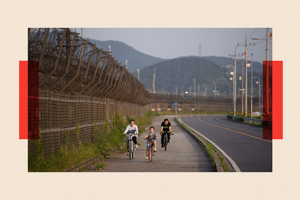 People on bicycles along a barbed wire fence of the Demilitarized Zone
