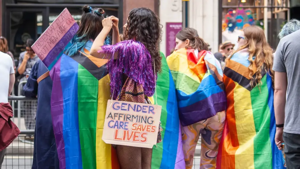 An activist wears a sign that says “gender-affirming care saves lives.”