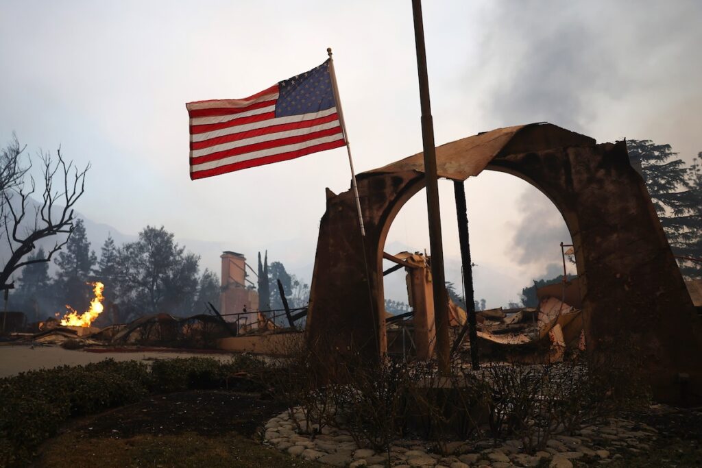 An American flag flies amid burned structures at the Altadena Town & Country Club during the Eaton Fire in Altadena, California