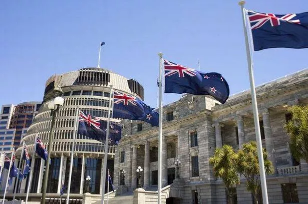 New Zealand flags flying in front of the Beehive and New Zealand's Parliament House.