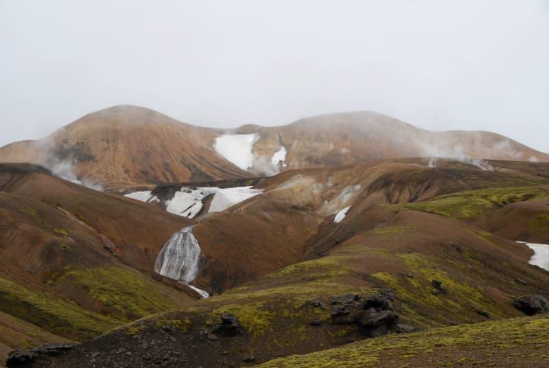The steam rises from hot springs while snow lies beside them - there's never a dull moment on an Icelandic hike. Finn Huwald/dpa-tmn