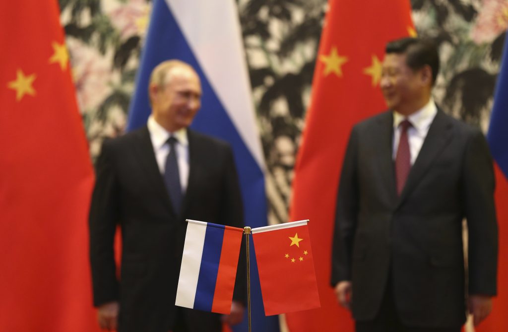 Photo: Russian and Chinese national flags are seen on the table with Russian President Vladimir Putin (L) and his Chinese counterpart Xi Jinping stand in the background during a signing ceremony at the Diaoyutai State Guesthouse in Beijing, November 9, 2014. Credit: REUTERS/How Hwee Yong/Pool.