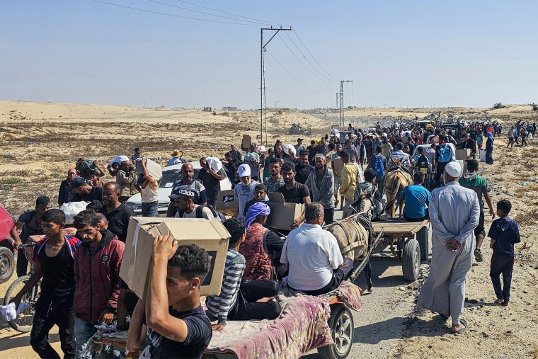 Displaced Palestinians walk along a road.