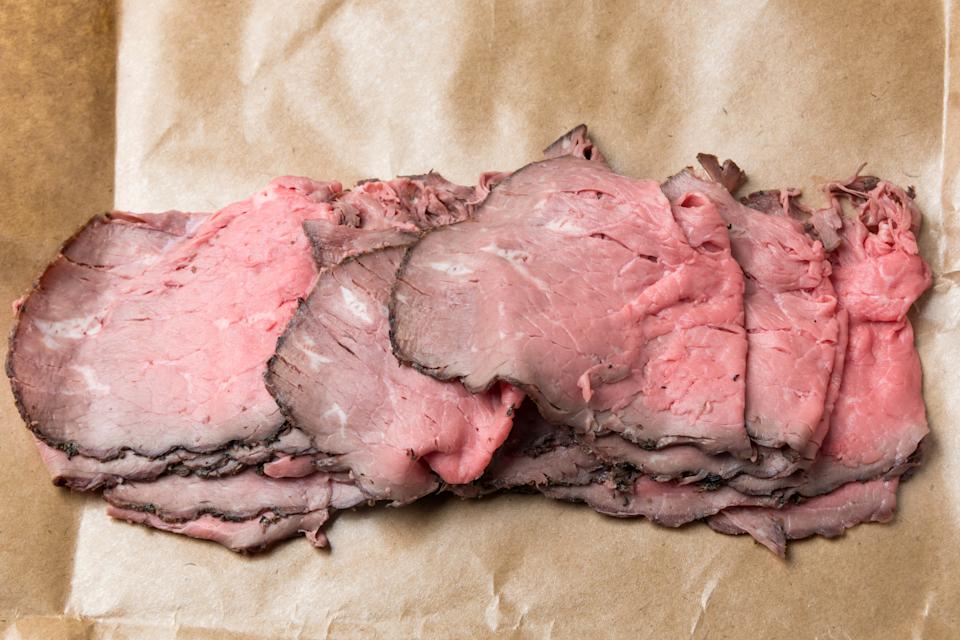 A heap of sliced roast beef on parchment paper.