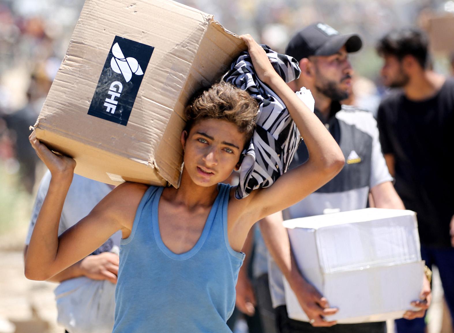 A boy carries a box of relief supplies from the Gaza Humanitarian Foundation, a private US-backed aid group that has bypassed the longstanding UN-led system in the territory, as displaced Palestinians return from an aid distribution centre in Gaza. Photo: AFP