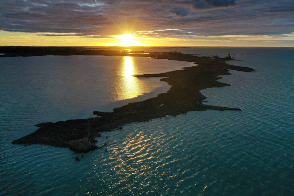 The image shows the sun near the horizon, reflecting off the water