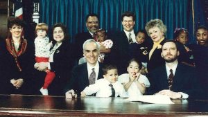 group of kids and families sitting at an executive desk for a photo op