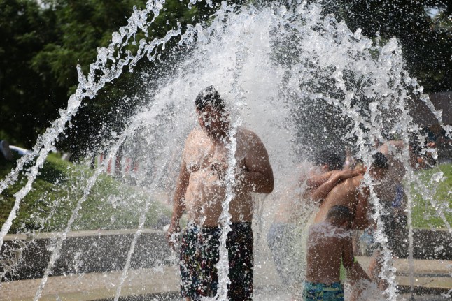 People cool off underneath water fountains in Madrid