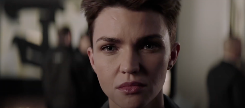 Person with short hair looking directly at the camera, focused and determined in an indoor setting