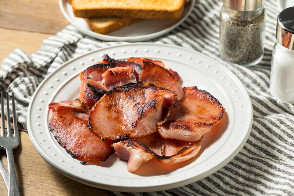 Homemade cooked Canadian bacon on a white plate.