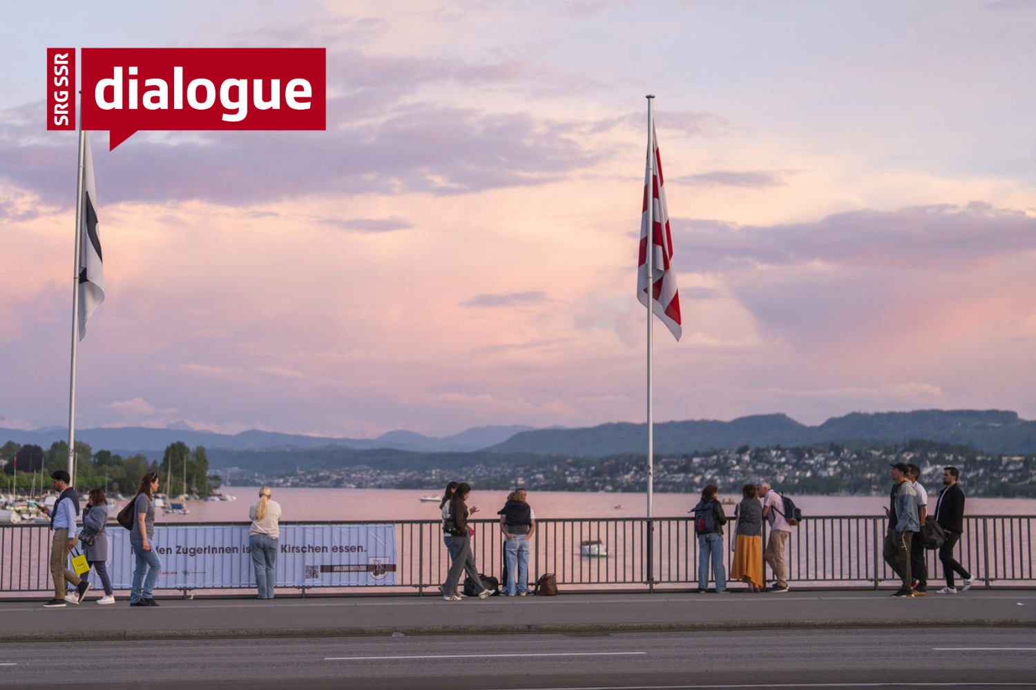 People are walking along a bridge at sunset.