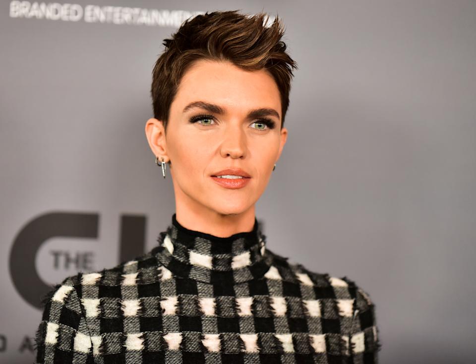Person with short hair in a high-neck, checkered outfit at an event