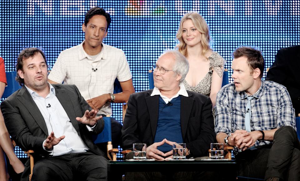 A group of actors and creators sit together, one in a suit gesturing expressively, during a panel discussion