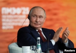 President Vladimir Putin applauds during a plenary session of the St. Petersburg International Economic Forum on June 20.